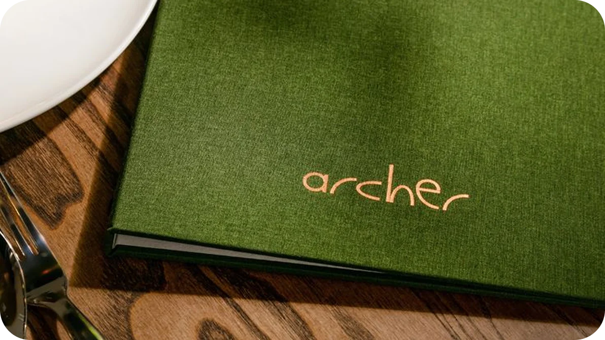 Green leather-bound restaurant menu on a wooden table